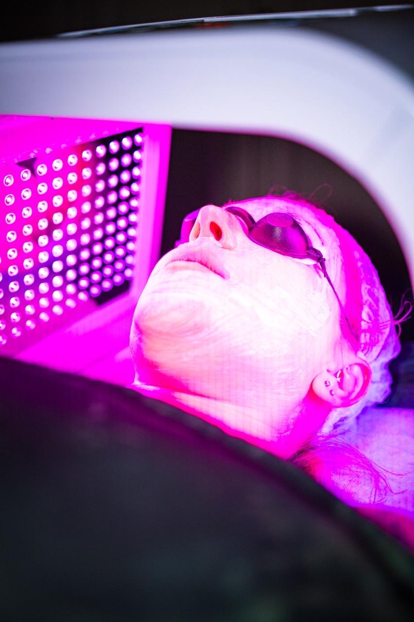 A client wearing protective eyewear beneath an LED light panel
