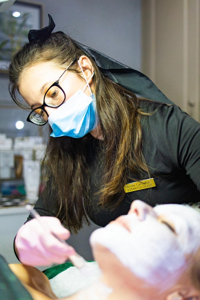 A skincare practitioner working with a client during a facial